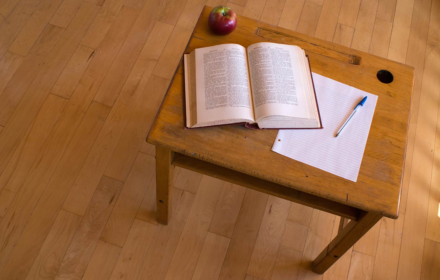 Holztisch auf einem Parkettboden mit einem Buch und Notizzettel darauf